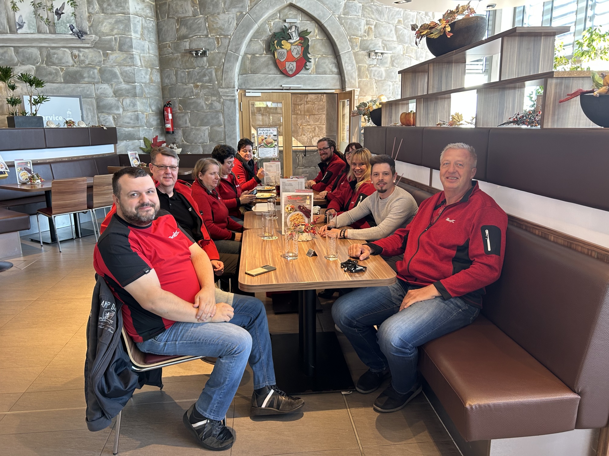 Unsere Mitarbeiter und Hr. Berger von BAT genießen an einer langen Tafel im Restaurant die Gerichte und lachen in die Kamera